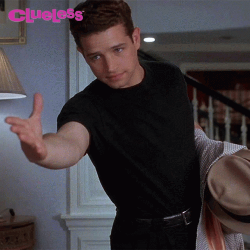 Man In Black Shirt Reaching Toward Lamp With Clueless GIF