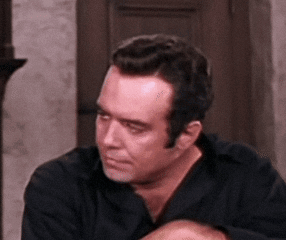 Man in Black Shirt Scratching Head