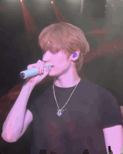 Man in Black Shirt Singing Into Microphone on Stage