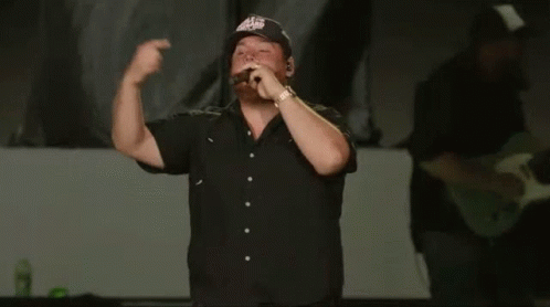 Man In Black Shirt Singing Into Microphone With Eagles Hat GIF
