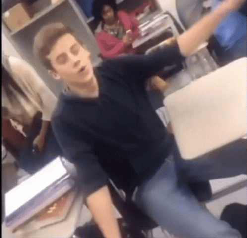 Man In Black Shirt Sitting At Desk With Arm Outstretched GIF