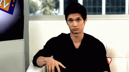 Man in Black Shirt Sitting in Front of TV Sign