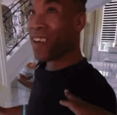 Man in Black Shirt Smiling in Front of Stairs