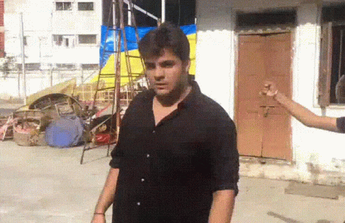 Man In Black Shirt Standing In Front Of Brown Door GIF