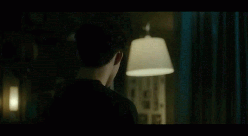 Man In Black Shirt Standing With Lamp In Dark Room GIF