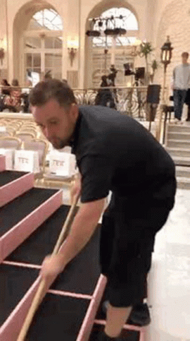 Man in Black Shirt Sweeping Floor