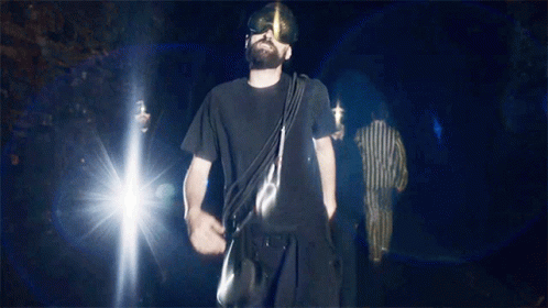 Man In Black Shirt Walking Dark With Bag GIF