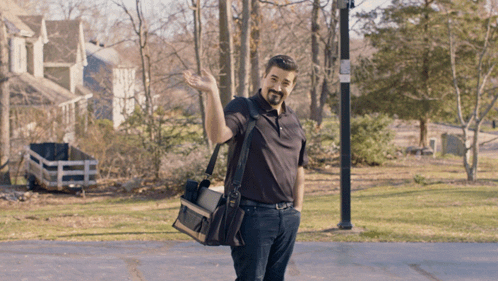 Man in Black Shirt Waving with Tool Bag