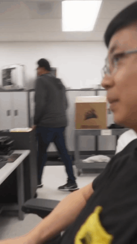 Man in Black Shirt With Yellow Stripe Looking at Box