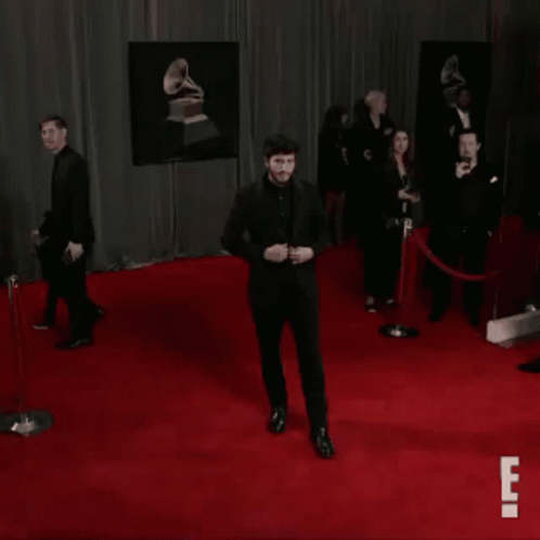 Man in Black Suit Dancing on Red Carpet