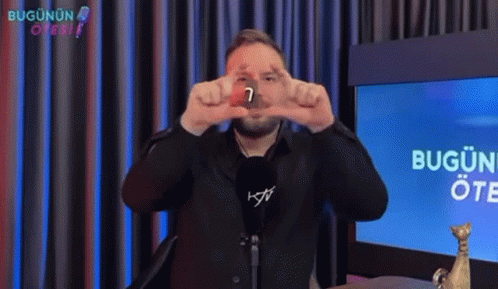 Man in Black Suit Making Hand Gesture in Front of Bugun Screen