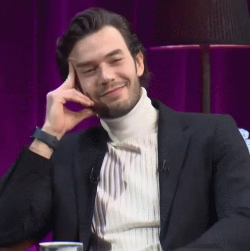 Man In Black Suit Smiling With Hand On Face GIF