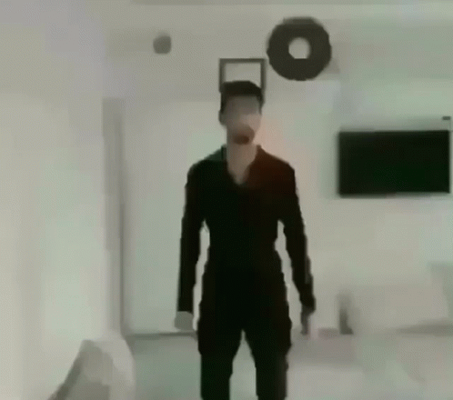 Man In Black Suit Standing In Living Room With Wreath GIF
