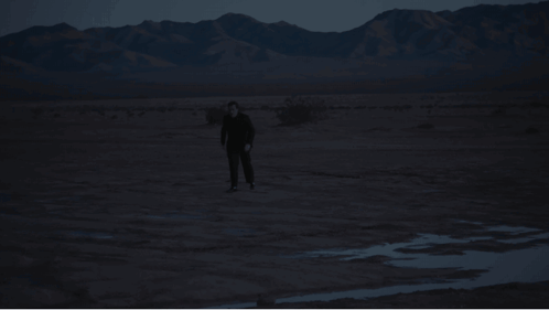 Man in Black Suit Walking in Desert