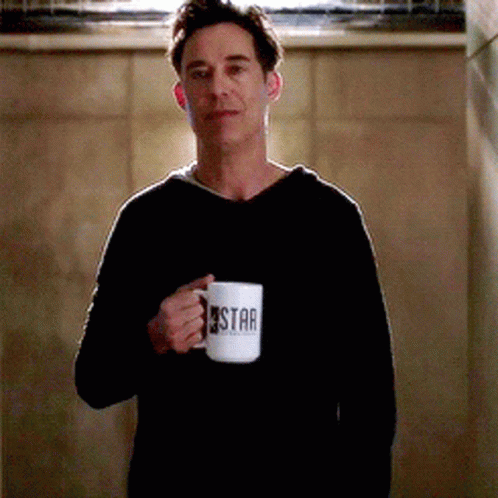 Man in Black Sweater Holding Coffee Mug Saying Star
