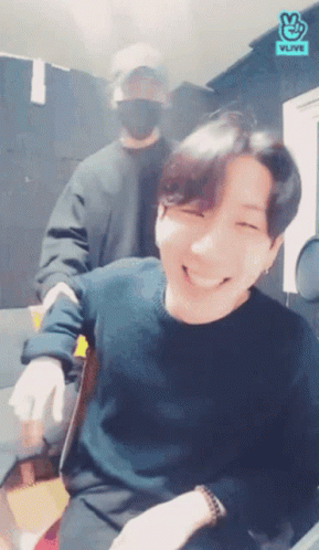 Man In Black Sweater Smiling With Another Man And Vlive Logo GIF