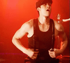 Man in Black Tank Top and Suspenders Holding Guitar