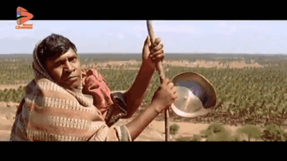 Man In Blanket Holding Pan And Stick GIF
