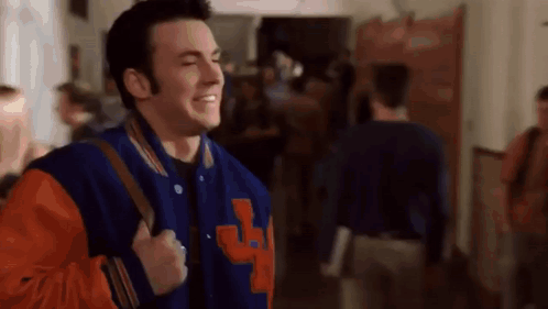 Man In Blue And Orange Varsity Jacket Walking With Backpack GIF