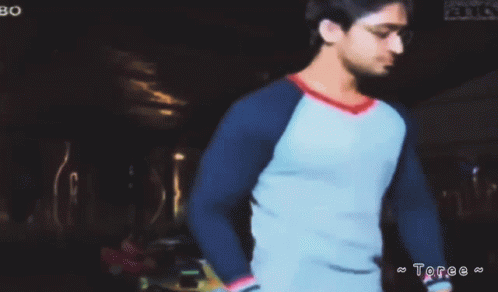 Man in Blue and White Shirt in Dark Room with Toree