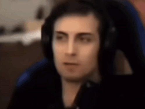 Man In Blue Chair Wearing Headphones Facing Camera GIF