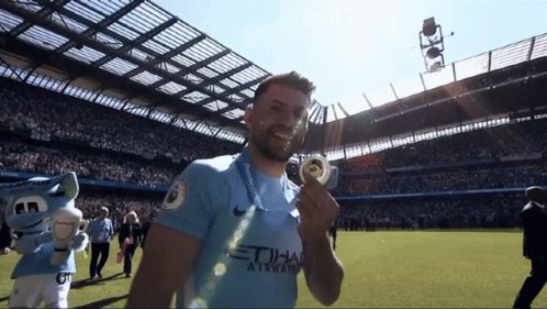 Man in Blue Etihad Airways Jersey Holding Medal