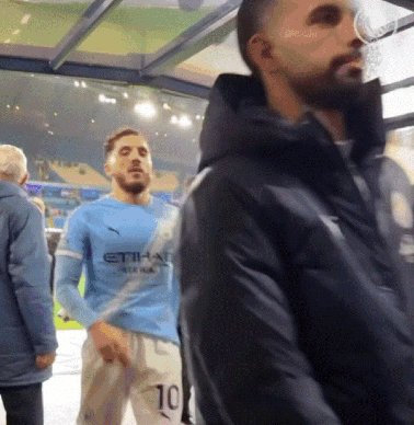 Man in Blue Etihad Jersey Beside Man in Black Jacket