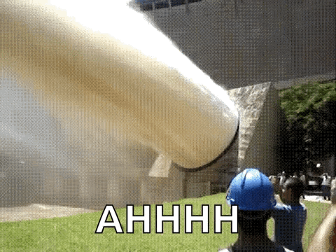 Man in Blue Hard Hat Near Spraying Pipe