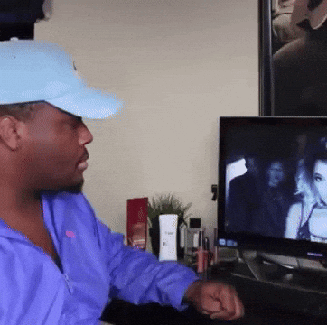 Man in Blue Hat and Purple Jacket Watching TV