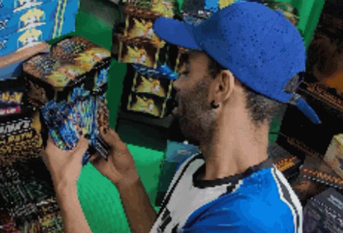 Man in Blue Hat Looking at Fireworks Box