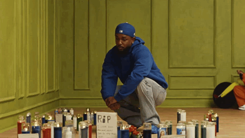 Man in Blue Hoodie Kneeling by Candles RIP Sign