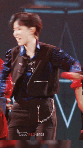 Man in Blue Jacket and Black Pants Dancing in Front of Redpanda Sign