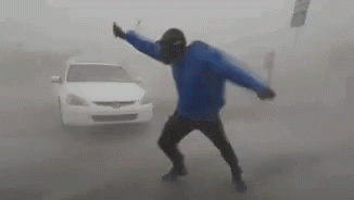 Man in Blue Jacket Dancing by Car in Fog