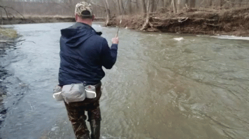 Man in Blue Jacket Fishing in Stream