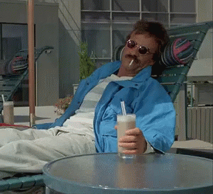 Man in Blue Jacket Holding Drink and Smoking