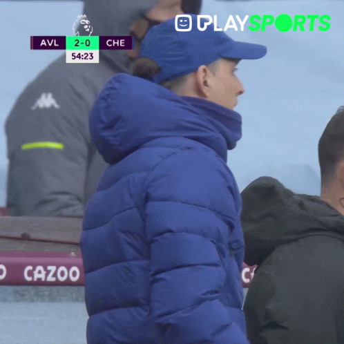 Man in Blue Jacket in Front of Scoreboard