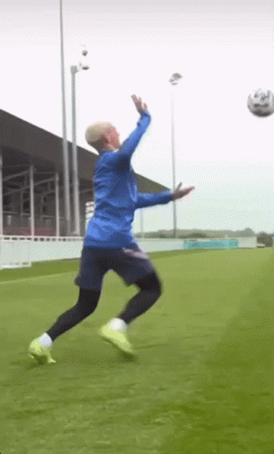 Man in Blue Jacket Jumping for Soccer Ball