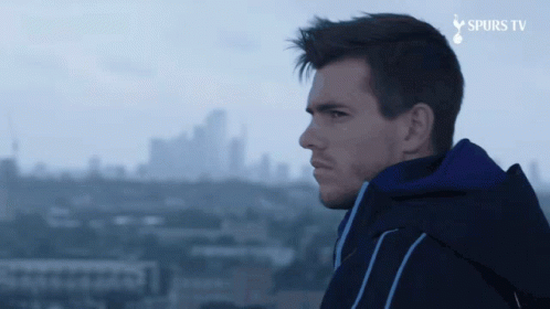 Man in Blue Jacket Overlooking City with Spurs TV