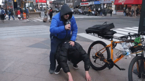 Man in Blue Jacket Pushes Leashed Man Next to Bike