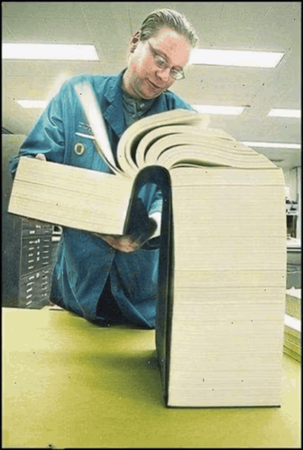 Man in Blue Jacket Reading Very Large Book