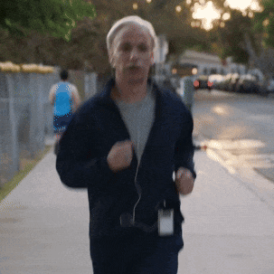 Man in Blue Jacket Running Down Sidewalk
