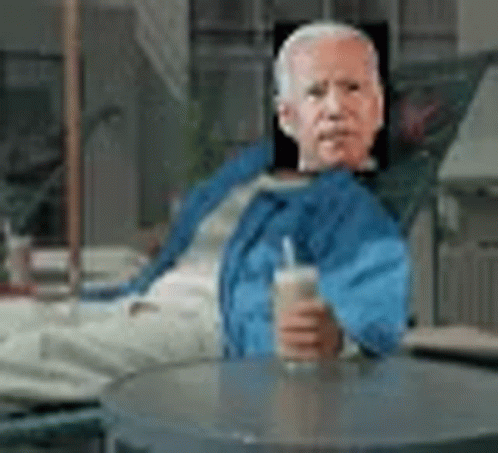 Man in Blue Jacket Sitting at Table With Drink