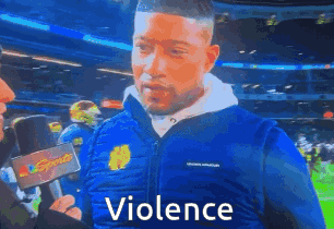 Man in Blue Jacket Talking Into Microphone With Violence