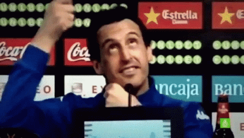 Man in Blue Jacket Thumbs Up in Front of Coca Cola and Estrella Ads