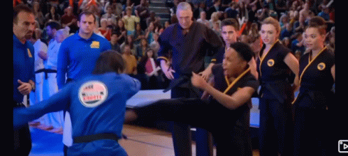 Man in Blue Jacket With Karate On Back Kicking Another Man