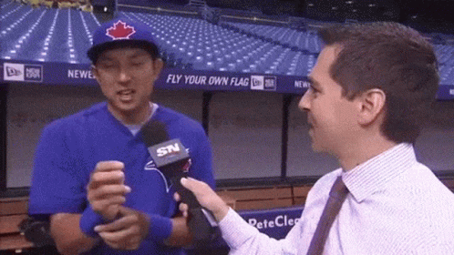 Man in Blue Jays Hat Interviewed by Man in Suit
