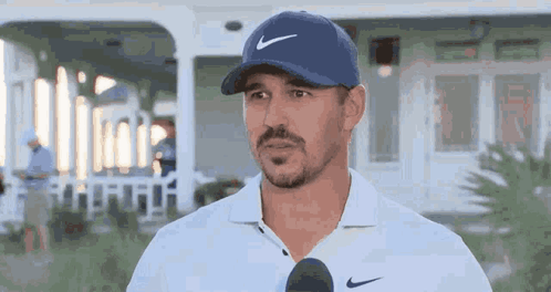 Man in Blue Nike Hat and White Shirt Talking Into Microphone