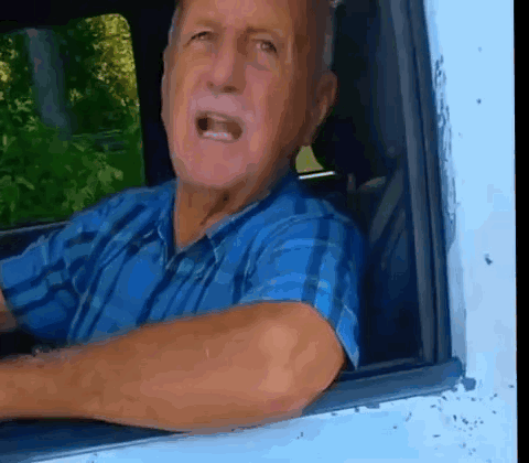 Man in Blue Plaid Shirt Looking Out Car Window