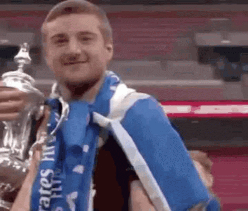 Man In Blue Scarf Holding Trophy GIF