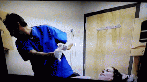 Man in Blue Scrubs Cleaning Patient's Face